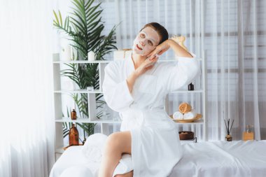 Kaplıca salonunun sakin, modern gün ışığı atmosferi, kadın müşteri poz veriyor ve yüz maskesi ile gençleştiriyor. Yüz bakımı ve güzellik kozmetolojisi prosedürü. Sessiz.