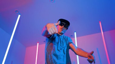 Beyaz dansçının gösterişli gözlükler taktığı ve break dans yaptığı alçak açılı kamera. Çekici adam kendinden emin bir şekilde kameraya bakarken enerjik bir performans ve hareket gösterdi. Mutluluk.