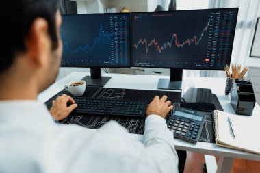 Akıllı tüccar işadamı, modern merkez ofisindeki araştırma pazarında en yüksek kârlı finansal teknolojiye yatırım yaparak bilgisayar üzerinde iki dinamik borsa yatırım ekranını analiz ediyor. Tahmin et..