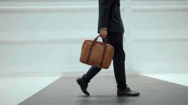 Profesyonel iş adamının bacağını tutarken yakın plan fotoğrafı. Proje yöneticisinin bacağa odaklanmış görüntüsü. Seyahat, taşınma, yolculuk, yürüyüş, yeni bir pozisyon alma, iş değiştirme. Sevinçli..