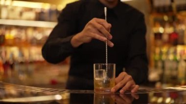 Zeki Asyalı barmen bardakta karıştırılmış alkol şurubunu buzla karıştırıyor. Çünkü kayanın üzerinde kamera var. Gece kulübünde taze kokteyl kokteylleri karıştırıyor. Vinosity.