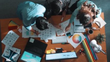 Tasarımcı fikirleri yazarken proje yöneticisinin yukarıdan aşağıya bakan görüntüsü. Akıllı iş adamları logo tasarımı fikrini açıklarken tasarımcılar palete bakarken temayı seçiyorlar. Sempozyum.