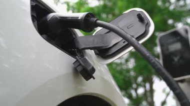 Yakın çekim yenilikçi modern ulaşım konsepti, elektrikli araba şarj istasyonunda gökyüzünden yansıyan yüksek detay ile şarj ediliyor. Yenilenebilir enerji tarafından kullanılan çevre dostu elektrikli araç.