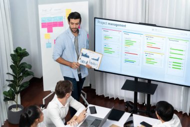 Proje yöneticisi monitörde proje yönetimi yazılım görüntülemesi, proje görevinin ilerlemesini izlemek ve toplantı masasında program planı yapmak suretiyle ekiple iletişim kurar ve işbirliği yapar. Tedbirli