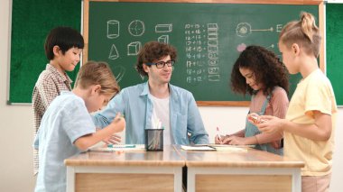 Zeki öğretmen, çeşitli çocuklar sınıf çalışması yapmak için birlikte çalışırken farklı çocukların zihin haritası çizdiği fikri açıklıyor. Çekici eğitmen öğretmek ve çalışmak hakkında konuşmak. Pedagoji.