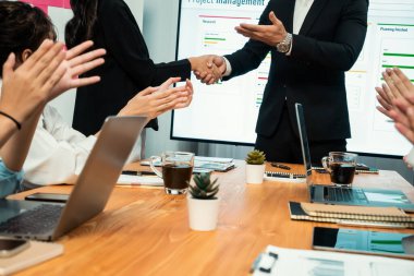 Neşeli toplantı odası, iş adamları el sıkışarak kutluyor. Başarılı proje son teslim tarihinden önce tamamlandı. İş ortaklığı ve proje yönetiminde işbirliği. Habiliment