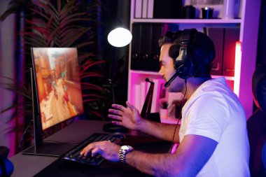 Akıllı oyun flaması dijital neon ışıklı siber odada kulaklık takarak bilgisayar ekranında çoklu ya da tek oyuncuyla çevrimiçi atış oyunu oynayan bir savaş takımı ile oynamaktan zevk alır. Tahmin et..