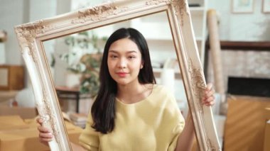 Girişimci elinde resim çerçevesi tutarken elinde nakliye siparişlerinin dağıtıldığı bir paket vardı. Asyalı satıcı kameraya özgüvenle bakıyor ve ürünü sunuyor. Myrmidon.