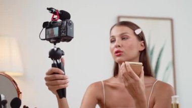 Sosyal medya için güzellik ve kozmetik video içeriği hazırlayan genç bir kadın. Güzellik blogcusu kameraya gülümserken seyircilere ve takipçilere güzellik bakımını gösteriyor. Düzenle