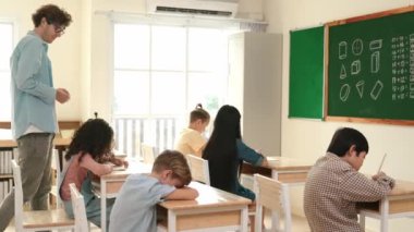 Öğrenci ödevlerine bakarken sınıfta yürüyen yetenekli bir öğretmen. Sınav yaparken ya da sınıfta ödev yaparken akıllı çocuk defterini kontrol eden profesyonel bir eğitmen. Pedagoji.