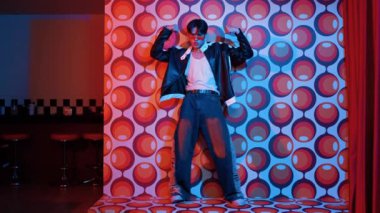 Asyalı break dansçı serbest stile geçiyor ve balon arka planlı kameraya bakıyor. Profesyonel hippi gündelik kıyafet giyer ve gözlük takar. Mutluluk.