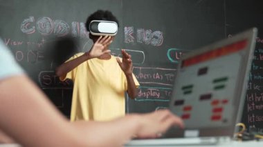 VR kullanan Afrikalı öğrenci meta-dünya ile etkileşime girerken liseli kız el kodlama programını kapat. Zeki çocuk sanal gerçeklik gözlüğü takıyor ve yenilikçi sınıfta video oyunları oynuyor. Öğretim