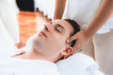 Beyaz adam stres önleyici kafa masajından ve lüks bir tatil beldesi veya otel spa salonundaki modern ışık ortamında yüz güzelliği eğlencelerini şımartmaktan hoşlanıyor. Sessiz.