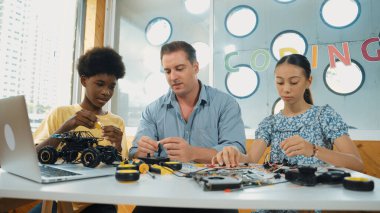 Yetenekli öğretmen çeşitli öğrencilere kablo ve elektronik ekipman kullanarak araba modelini tamir etmeyi öğretiyor. Bilgisayara bakarken ana kartı kontrol etmek için elektrikli alet kullanmayı öğrenen bir kız. Öğretim