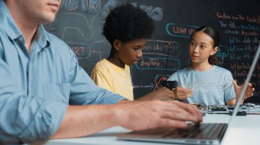 Genç öğrenci BTMM sınıfında öğretmenlik yaparken denetleyiciyi tamir ediyor. Akıllı kız elektronik alet ve karatahta kullanırken eğitmen el bilgisayarı. Öğretim.