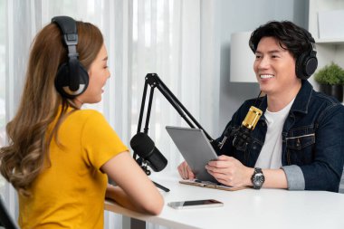 Gülümseyen radyo etkili sunucu elinde tablet, kulaklık takıyor kadın konuşmacı sosyal medya online canlı yayın kanalı ile röportaj yapıyor ve sabah stüdyo kaydında paylaşım linkini paylaşıyor. İnfobahn.