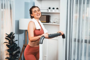 Spor ve atletik bir kadın, evdeki fiziğe ve sağlıklı spor yaşam tarzına uygun vücut egzersizi sırasında koşu bandında koşuyor. Gaiety evde egzersiz eğitimi.