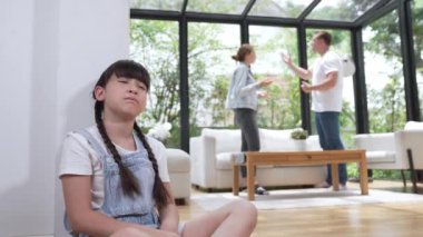 Stresli ve mutsuz genç kız köşeye kıvrılıp kulaklarını kapatarak arka planda ebeveyninin tartışmasını engelliyor. Evde aile içi şiddet ve travmatik çocukluk depresyona dönüşür. Titiz