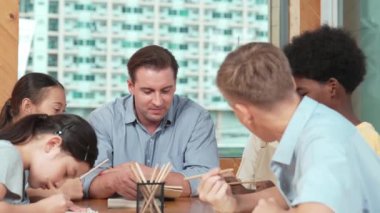 Sıradan tişörtlü zeki liseli çocuk, karışık ırkları olan öğrenciler kitap yazarken profesyonel öğretmene soruyor. Yaratıcı çocuk notayı işaret ederken Kafkas eğitmeni yorum yapıyor. Öğretim