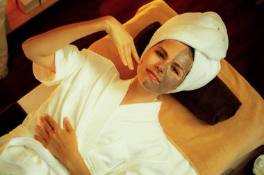 Kaplıca salonunun sakin atmosferi, üst düzey kadın müşteri sıcak mum ışığında kömür kömürü yüz kremi masajıyla kendini yenilemeye çalışıyor. Yüz bakımı ve güzellik konsepti. Sessiz.