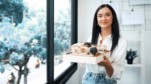 Крупный план квалифицированного молодого красивого кавказского архитектора лифта дом модели левой и правой стороны, чтобы проверить и сосредоточиться на проверке ошибок точки в современном офисе с чертежом. Непорочный.