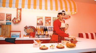 Profesyonel Asyalı restoran işçisi yemek hazırlar ve yemek barının arkasında durur. Kırmızı önlüklü çekici garson kameraya bakarken vişne topluyor. Çılgın dans. Mutluluk.