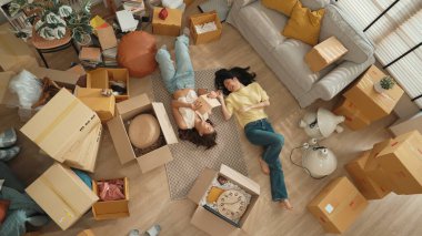 Oturma odasının zemininde karton kutuyla çevrili yatan lezbiyen çiftin hikayelerini kitapla paylaşırken en tepeden aşağıya bakışı. Mutlu aşıklar birlikte vakit geçirir ve birlikte gülerler. Myrmidon.