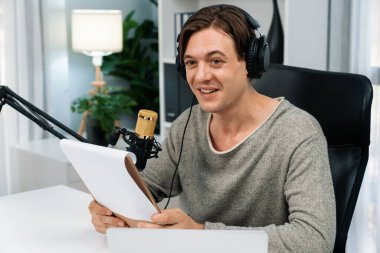 Akıllı yayıncının sunucu kanalı canlı sosyal medya yayını ile dinleyicilere senaryo okuyarak, kulaklık takarak modern ev stüdyosundaki video flamalarını kaydediyor. Bireysel.