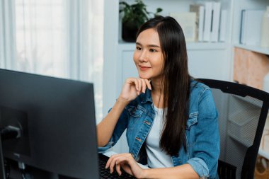 Genç ve güzel Asyalı yaratıcı yönetici bilgisayar üzerinde çalışıyor, yeni bir web sitesi tasarımı ile yeni sosyal medya çevrimiçi kanal planlaması üzerinde modern ev ofisinde kot pantolon gömleği ile çalışıyor. Taktik.