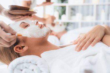 Kaplıca salonunun sakin atmosferi, modern gün ışığında lüks yüz kremi masajıyla gençleşmeye hevesli çiftler. Yüz bakımı ve güzellik konsepti. Sessiz.