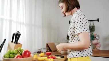 Kafkaseli anne kahvaltıda sebze pişirirken mutlu anne de modern mutfakta salata için taze malzemeler hazırlıyor. Hizmetçi sağlıklı yemek pişiriyor. Dikkat konsepti. Pedagoji.