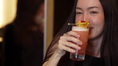 Paloma 'da fermuarlı kokteyl içen gülümseyen güzel bir kadın vişneli limon özel menüsüyle süslenmiş hoş bir içecek, lüks bir barda arkadaşla sıcak bir gece kulübü partisinde ferahlatıcı bir içecek. Vinosity.