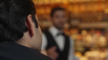 Profesyonel takım elbiseli akıllı barmen, lüks tezgah barında VIP müşteriyle konuşuyor. Bar ve restoran atmosferinde gece hayatı. Özel içecek ve içecek menüsü. Vinosity.