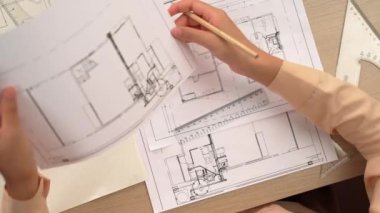 Ölçüm aracı ve kalem kullanan akıllı mimar ya da mühendisin videosu mimari ofisteki inşaat doğruluğu için bir el taslağı ayrıntılı taslağını karşılaştırıyor. Eline odaklan. - Yakın çekim. Tanımlama.