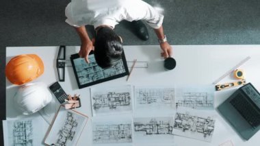 Bina yapısını analiz etmek için dizüstü bilgisayar kullanırken tablete bakan mühendislerin yukarıdan aşağı görüntüsü. Proje planıyla toplantı masasında iç tasarımı kontrol eden mimarın hava görüntüsü. Hizalama.