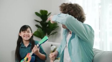 Beyaz bir baba akustik müzik dinlerken tatlı bir kız gitar çalıyor. Sevgili baba ukulele kullanırken şarkı söyleyerek dans ediyor. Yetenekli öğrenci de müzik öğreniyor. Yaratıcı aktivite konsepti. Pedagoji.