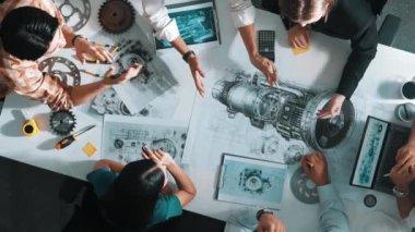 Türbin motoru tasarlamak için çalışan akıllı mühendis takımının yukarıdan aşağıya hava görüntüsü. Profesyonel teknisyen jet motoru yapımını tartışırken motorun bir kısmını işaret ediyor. Hizalama.