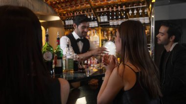 Dumanlı, klasik kokteyl içmiş çift ile VIP müşterilere özel içki servisi yapmak güzel kokuyor. İçki tezgahının lüks barında akıllı barmenlerin açtığı viski kokteyli. Vinosity.