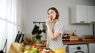 Modern mutfakta meyve doğrayan ve elma yiyen enerjik Kafkas akıllı ev bekçisi. Çekici anne kameraya bakarken salata yapmaya hazırlanıyor ve elma tatma havasında. Pedagoji.
