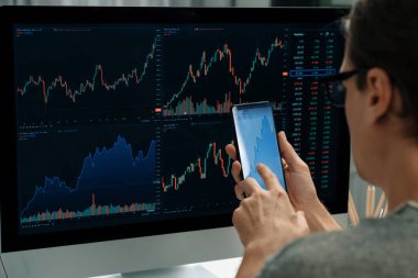 Akıllı borsa yatırımcıları ekranda akıllı telefon ile piyasa borsasını işaret ederek dizüstü bilgisayarın yanı sıra en yüksek dinamik yatırım oranını göstererek, modern işyerindeki veri planlamasına odaklanıyorlar. Bireysel.