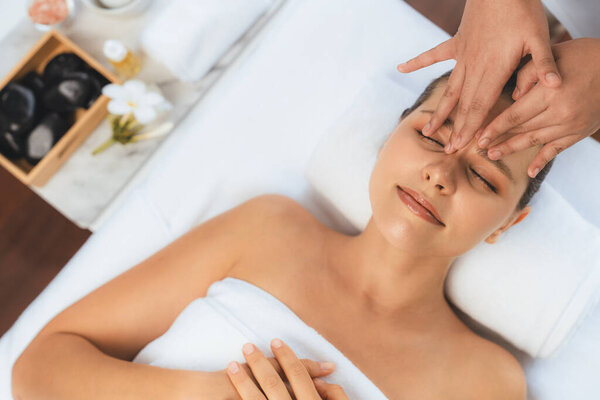 Panorama top view of woman enjoying relaxing anti-stress head massage and pampering facial beauty skin recreation leisure in dayspa modern light ambient at luxury resort or hotel spa salon. Quiescent