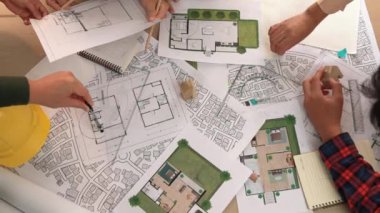 Mimari belge, ölçüm aracı ve ahşap blokların modern ofiste etrafa saçıldığı bir masa üzerinde yapı inşaatı ile ilgili mimar ve güvenlik mühendisi tartışması. Tanımlama.