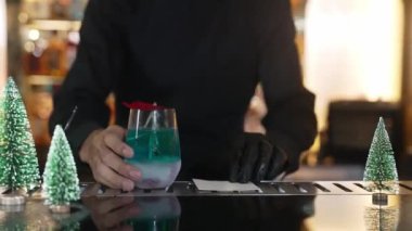 Barmen, kırmızı kurutulmuş meyve biberiyesi ile mavi lagün kokteylini VIP grup konuğu veya yeşil neon karlı Noel ağacı festivalinde bir çiftle servis ediyor. Vinosity.