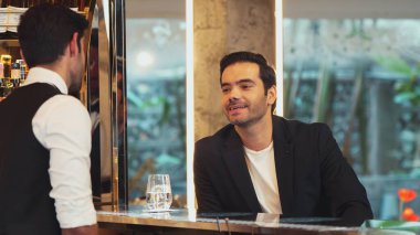 Tezgahta oturup barmenle konuşan zeki müşteriler gece kulübü lüksünde içki listesi tavsiye eden profesyonel barmen kostümü için harika bir izlenim bırakıyorlar. Vinosity.