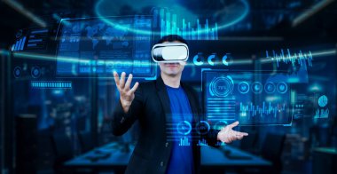 VR gözlüklü proje yöneticisi mali tabloya bakıyor ve ofiste mavi ışık parlıyor. Yetenekli iş adamı artırılmış gerçeklikten elde edilen verileri kullanarak pazarlama stratejisini kontrol edip planlıyor. Yaratıcılık.