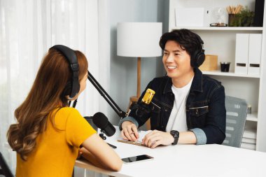 Gülümseyen radyo etkili sunucusu kulaklık takıyor kadın konuşmacı ile röportaj yapıyor sosyal medya internet sitesinden dinleyicilere bilgi paylaşıyor stüdyo kaydında sabah canlı yayın kanalı. İnfobahn.