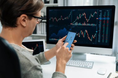 Akıllı borsa yatırımcıları ekranda akıllı telefon ile piyasa borsasını işaret ederek dizüstü bilgisayarın yanı sıra en yüksek dinamik yatırım oranını göstererek, modern işyerindeki veri planlamasına odaklanıyorlar. Bireysel.