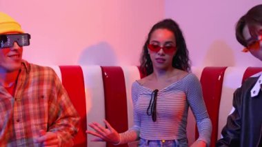 Mutlu kız kameraya bakıyor ve kanepede otururken pop müzik dinliyor. İspanyol kadın serbest stil dans ederken kameraya bakıyor neon ışıkta çeşitli arkadaşlarla dans ediyor. Mutluluk.