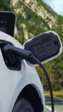 Elektrikli araç konsepti, yeşil çevre için yenilenebilir ve temiz enerjiyle çalışan EV otomobilinin varış noktasına ulaşmadan önce ormandaki şarj istasyonunun enerjisini şarj etmek için durur..