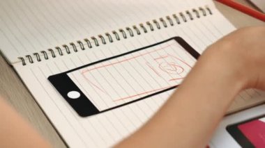 Mobil uygulama için kullanıcı arayüzü prototipi ya da masadaki program modeliyle birlikte web sitesi planlaması yapan bir şirket çalışanı. UX UI tasarımcısı kullanıcı dostu arayüz planını dikkate alır. Sinerjik